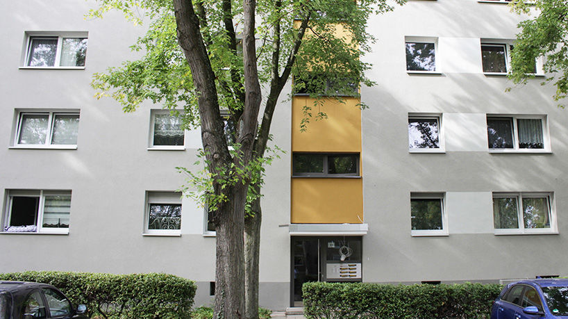 Saniertes Mehrfamilienhaus mit grau-gelbem Fassadenanstrich
