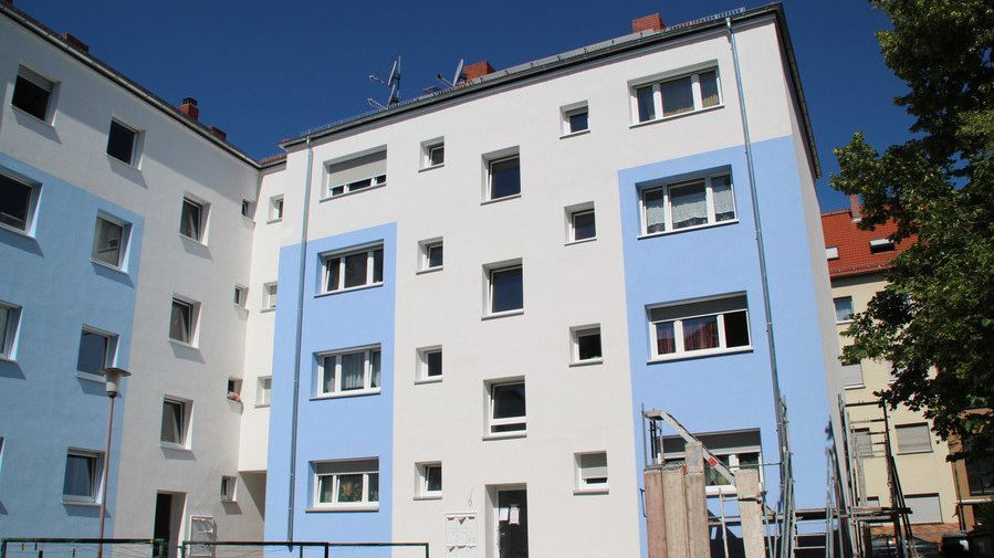 Mehrstöckiges Wohnhaus mit blau-weißem Fassadenanstrich