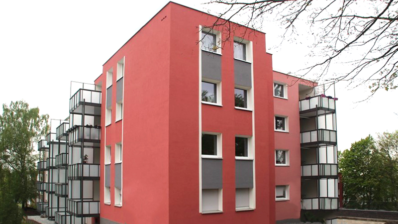 Mehrfamilienhaus mit rotem Fassadenanstrich